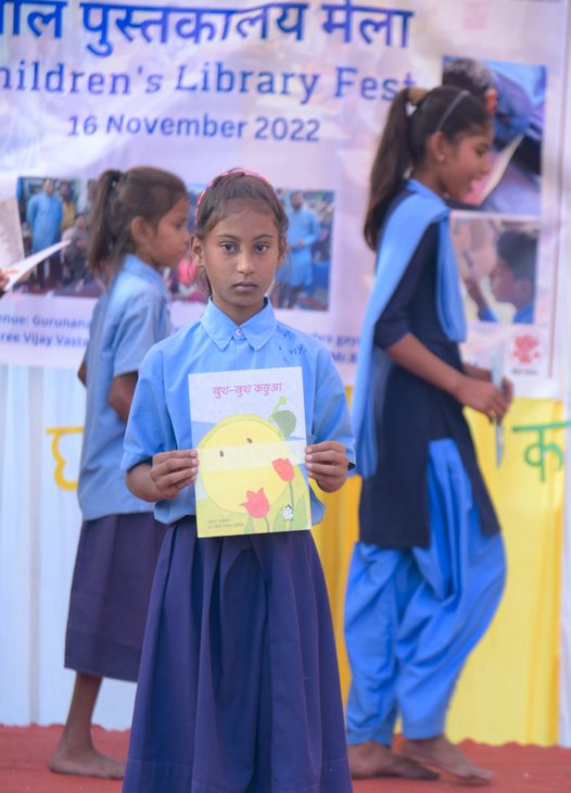 A girl in school uniform holding a book at a children's library fest