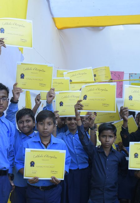 Students in uniform holding certificates of participation