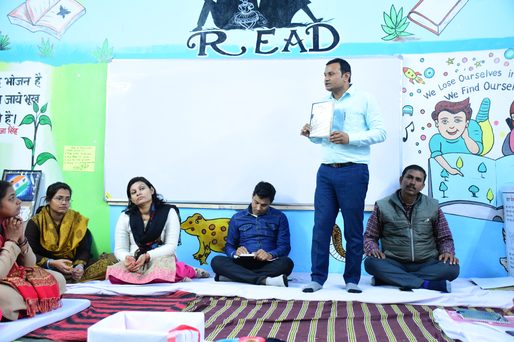 Children and adults seated together in a classroom reading circle