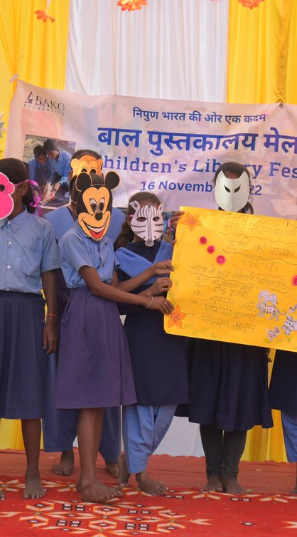 Children performing in costumes and masks on stage